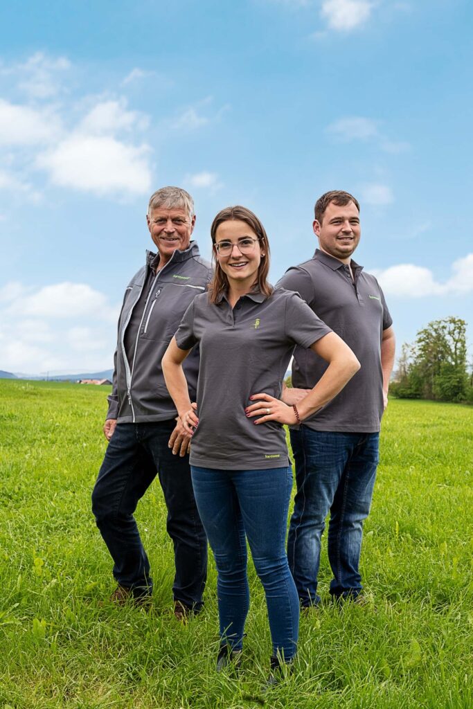 Drei Farmsaat-Mitarbeitende stehen freundlich lächelnd auf einer Wiese